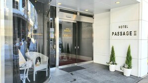 A hotel entrance with a glass door, a wicker chair outside, and potted plants. - Hotel Passage 2 (Aomori)