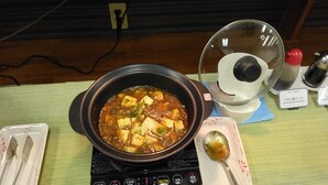 A hot pot setup with a bowl of stew, a spoon, and a portable heater on a table. - Hotel Passage 2 (Aomori)