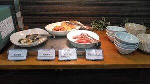 A buffet table with various dishes, including seafood and sushi, and labeled signs indicating different food options. - Hotel Passage 2 (Aomori)