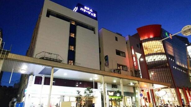 A modern building with a prominent sign, a covered entrance, and a brightly lit corner. - Hotel Passage 2 (Aomori)