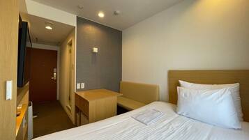 Una habitación de hotel con una cama, una mesita de noche y un escritorio pequeño.