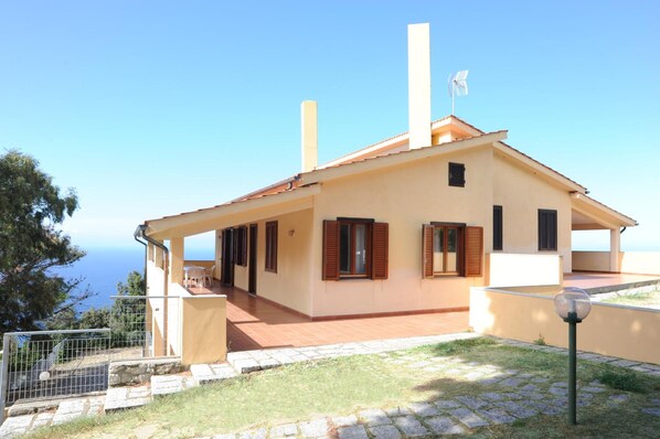A two-story house with a balcony, a view of the sea, and a fenced garden area. - Il Castagno (Marciana)