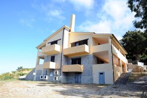 A modern two-story building with a flat roof, multiple balconies, and a stone facade. - Il Castagno (Marciana)