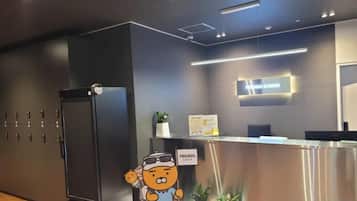 A hotel reception area with a modern design, including a reception desk, a refrigerator, and a sign indicating a 'Friends' lounge.