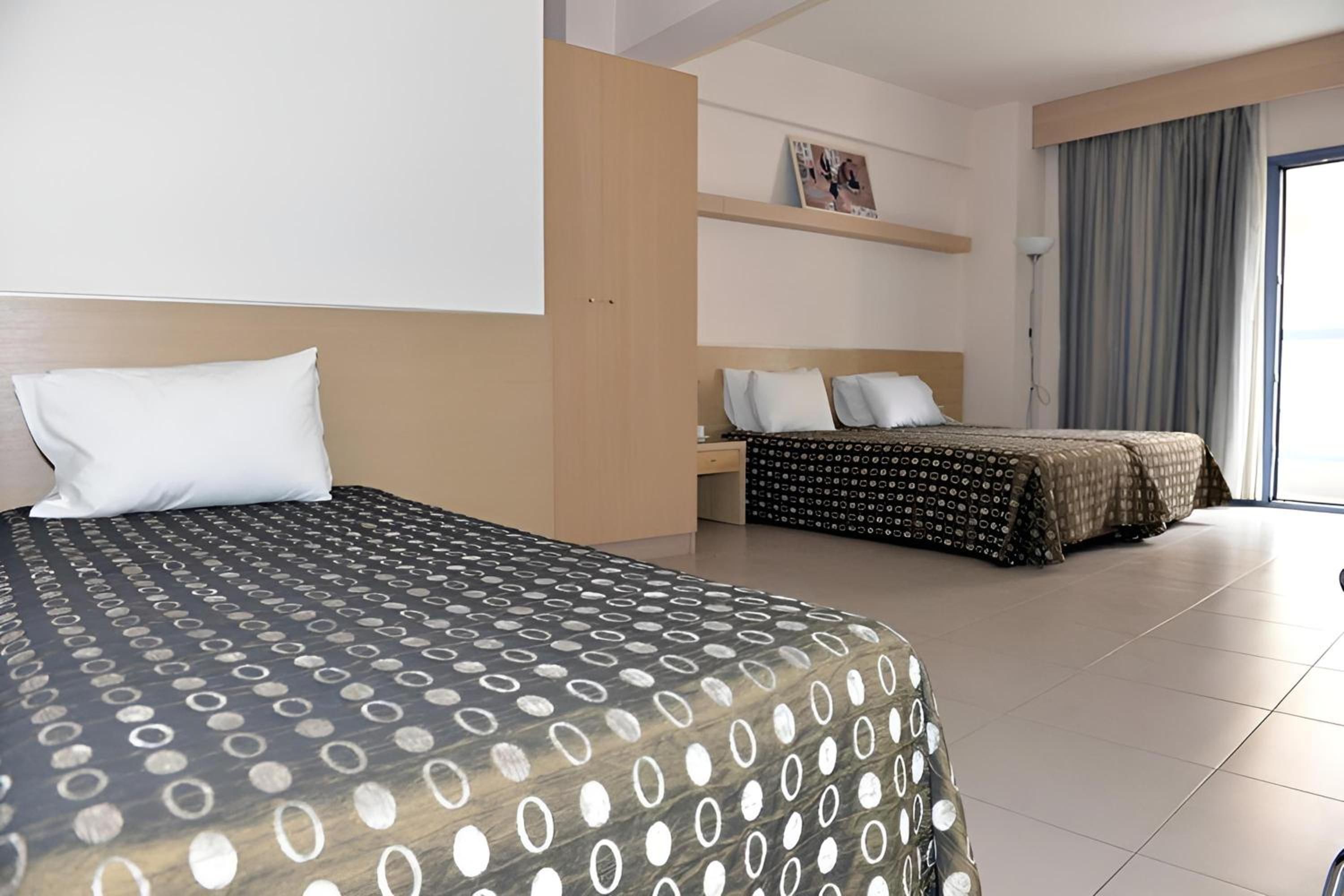 Ein Hotelzimmer mit zwei Betten, einem großen Fenster und Blick ins Freie.