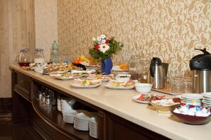 A buffet table with various food items, a vase of flowers, and condiments. - Hotel Hermes (Alba Iulia)