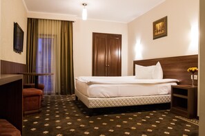 A hotel room with a bed, a desk, a chair, a wardrobe, and a painting on the wall. - Hotel Hermes (Alba Iulia)