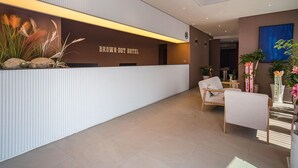 A reception desk with a sign reading 'BROWN-DOT HOTEL,' a seating area with chairs, and potted plants. - Brown Dot Hotel Eurwangri (Incheon)