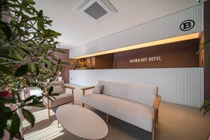 A modern hotel reception area with a sofa, chairs, a reception desk, and a plant. - Brown Dot Hotel Eurwangri (Incheon)