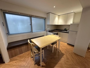 A compact kitchen with a dining table, bench seating, and a refrigerator. - Brown Dot Hotel Eurwangri (Incheon)