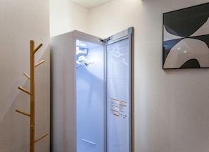 Een moderne lift met een glazen deur, een houten kapstok en een abstract kunstwerk aan de muur.