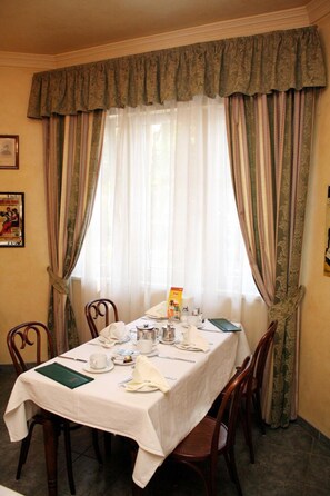 A dining room with a table set for two, featuring a white tablecloth, chairs, and a window with sheer curtains. - Lv Vay Villa Hotel (Miskolc)
