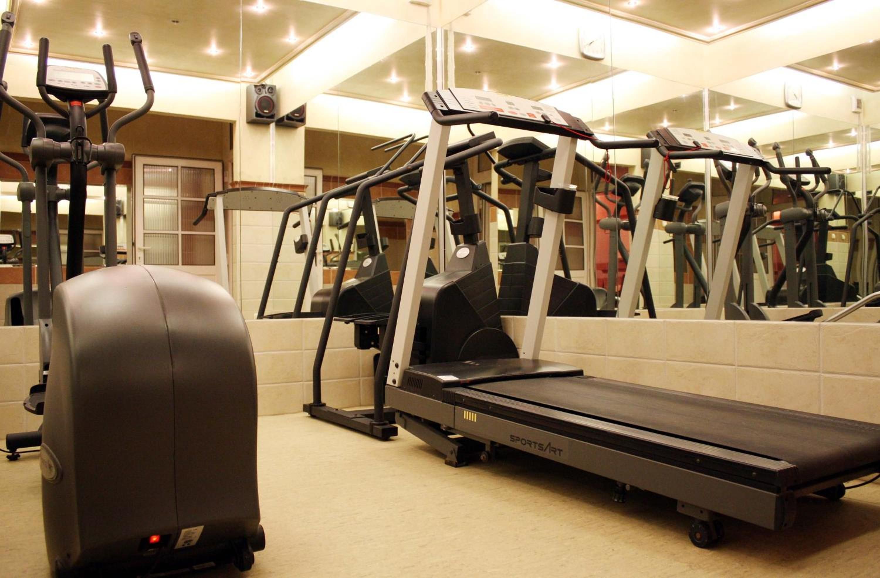 A gym with various exercise equipment including treadmills, stationary bikes, and elliptical machines.