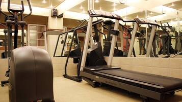 A gym with various exercise equipment including treadmills, stationary bikes, and elliptical machines.