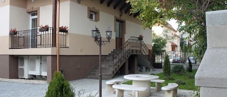 A building with a balcony, outdoor seating, and a staircase leading to an upper level.