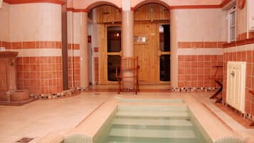 A spa area with a tiled floor, a wooden chair, and a small pool.