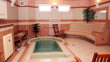 A spa room with a hot tub, a wooden bench, a chaise lounge, and a potted plant.