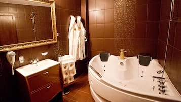 Un baño con una bañera grande, un tocador con espejo y un secador de pelo.