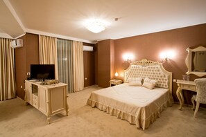 A hotel room with a large bed, a television, a dresser, and an air conditioning unit. - Hotel Diamond (Kazanlak)