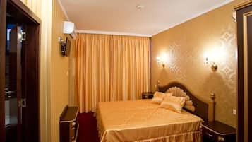 Una habitación de hotel con una cama grande, una mesita de noche, una lámpara de pared y una puerta con espejo.