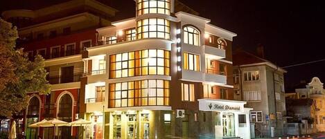 A multi-story hotel with a prominent corner entrance, large windows, and outdoor seating.