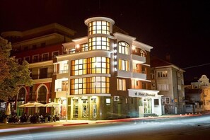 A multi-story hotel with a prominent corner entrance, large windows, and outdoor seating. - Hotel Diamond (Kazanlak)
