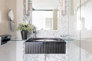 A modern bathroom with a glass sink, a potted plant, and a mirror. - Numa I Bona Rooms Apartments (Bonn)