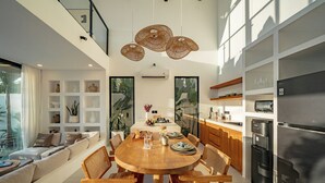 A modern kitchen with a central island, built-in appliances, and a dining area with a round table and chairs. - VIlla Ezra Azul (Uluwatu)