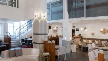 Eine geräumige Lobby mit hoher Decke, einer Treppe und einer Sitzecke mit modernen Möbeln.