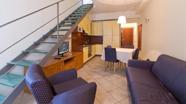 A compact living space with a staircase, kitchenette, dining area, and seating. - Palazzo Gallo (Palermo)