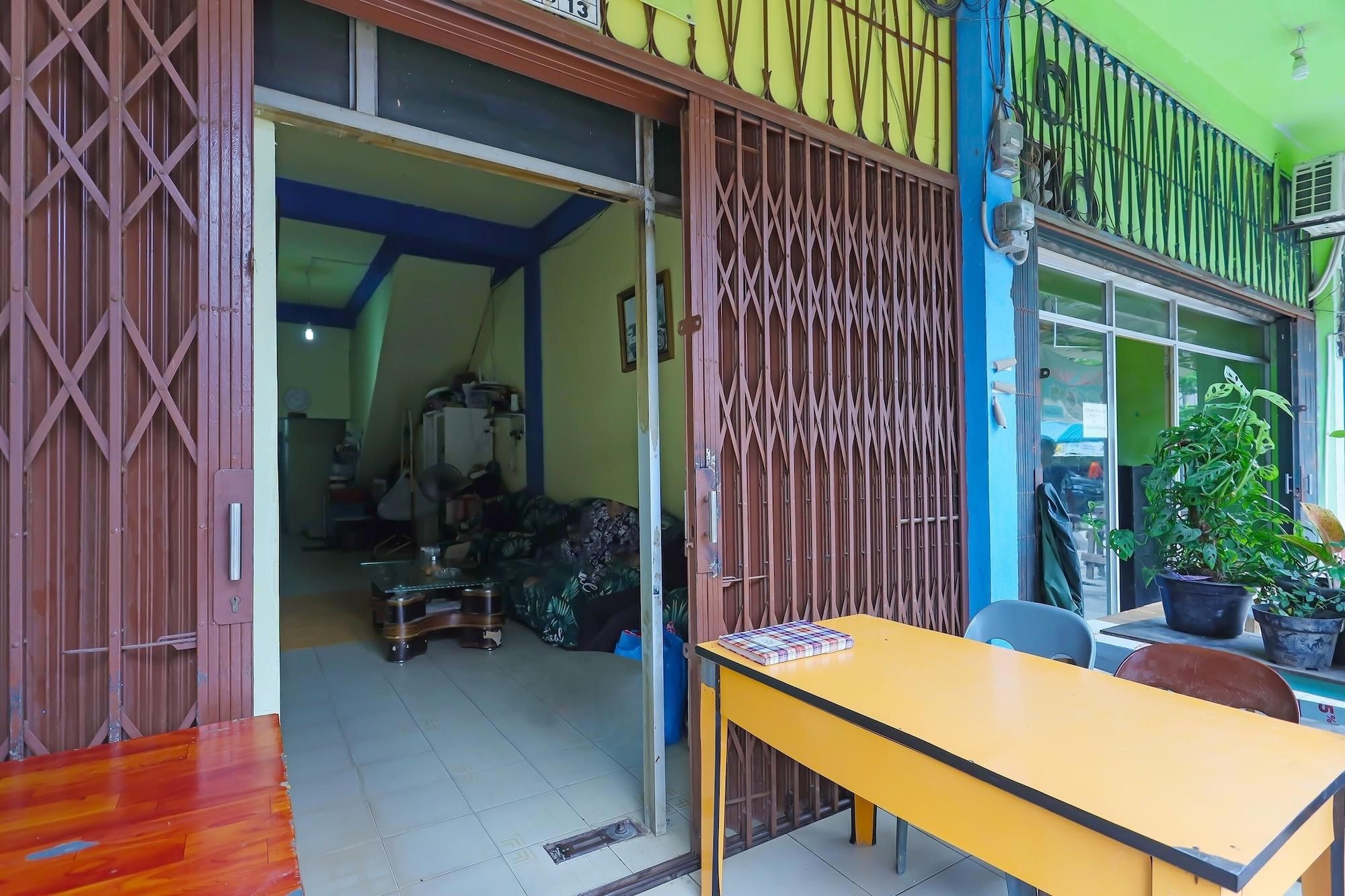 A room with a wooden door, a yellow table, and a potted plant.