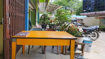A yellow table with a book, a potted plant, and a motorcycle parked outside.