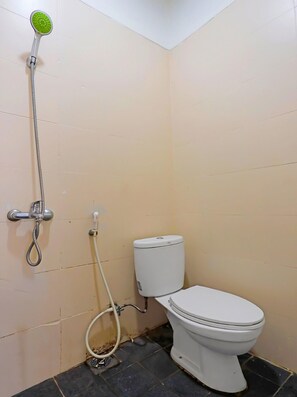 A small bathroom with a toilet, a shower head, and a toilet paper holder. - Spot On 92186 Penginapan Lorra (Batam)