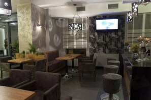A modern interior with seating arrangements, a bar area, and a television screen. - Hotel Vis A Vis (Olesnica)