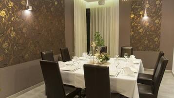 A dining room with a round table set for six, surrounded by dark chairs.