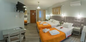 A hotel room with two beds, a desk, a chair, a TV, and an air conditioning unit. - Aklidi Hotel (Lesvos)