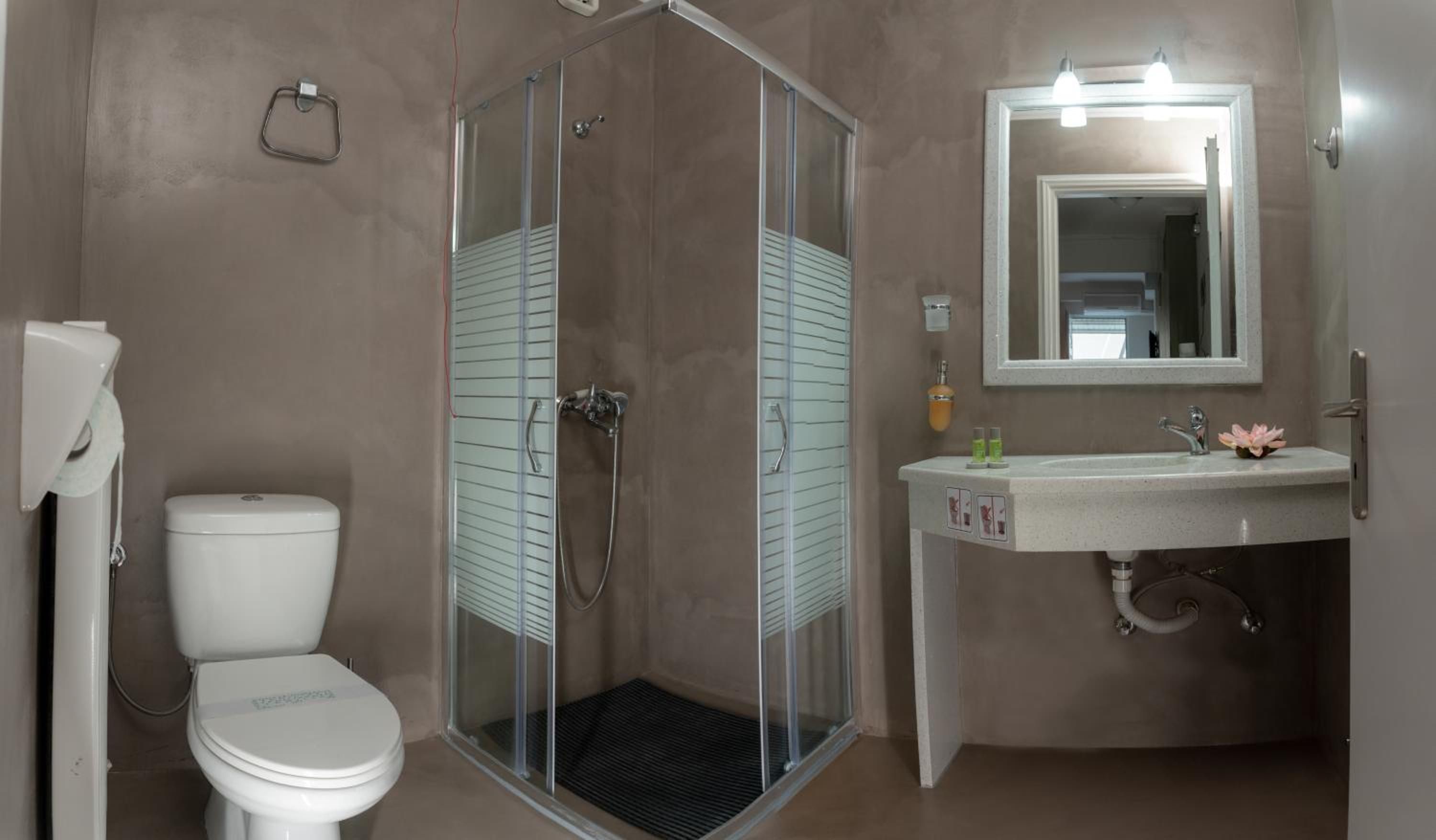 Un baño con ducha de mampara de vidrio, inodoro y lavamanos con espejo.
