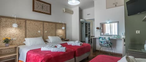 A hotel room with two beds, a desk, a chair, a TV, and a mirror.