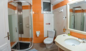 A bathroom with a glass-enclosed shower, a toilet, and a sink with a mirror. - Aklidi Hotel (Lesvos)