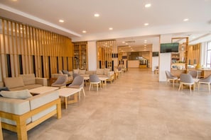 A spacious lobby with a modern design, featuring a seating area with sofas and chairs, a reception desk, and a television screen. - Nevis Resort (Nessebar)
