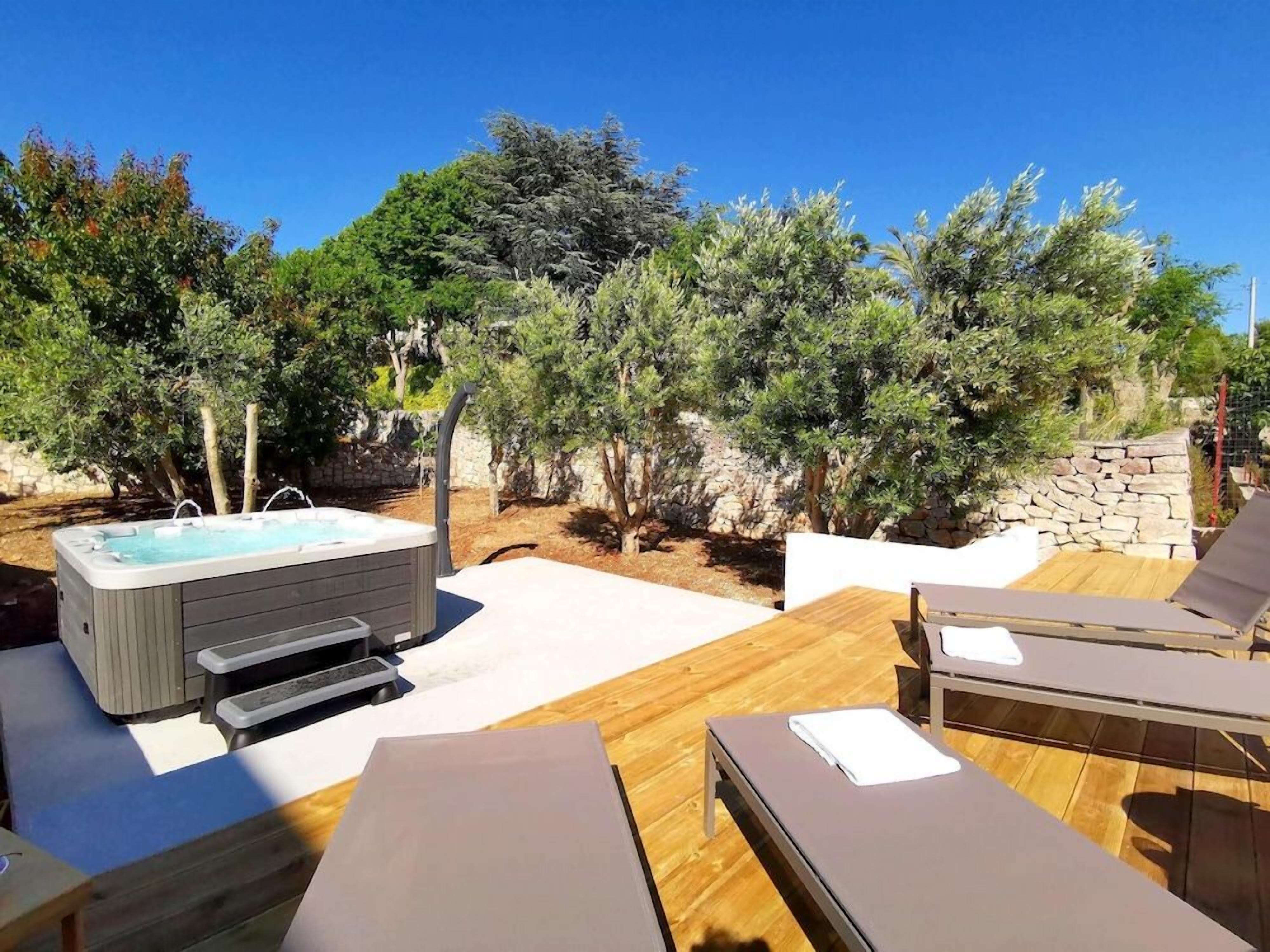 A hot tub with steps, wooden deck, and lounge chairs.