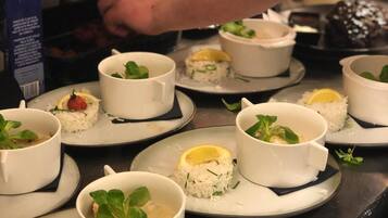 A chef preparing food in a kitchen with white bowls containing rice and garnishes on plates.