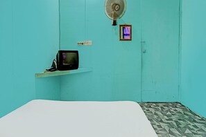 A room with teal walls, a bed, a small TV on a shelf, a fan, and a small window. - Spot On 92167 Jodoh Stay Syariah (Batam)