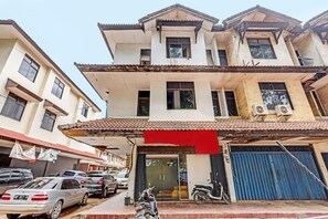 A multi-story building with a flat roof, a garage with a blue shutter, and parked cars. - Spot On 92167 Jodoh Stay Syariah (Batam)