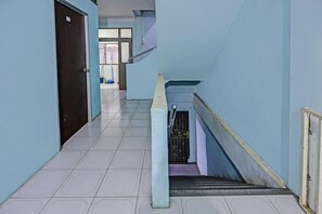 A hallway with a staircase, tiled floor, and a door on the left. - Spot On 92167 Jodoh Stay Syariah (Batam)