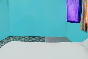Una habitación con una cama individual, piso estampado y cortina en la ventana.