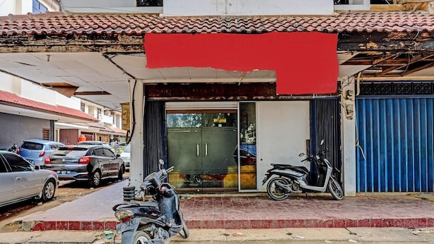 A building with a tiled roof, a closed shop with a glass door, and a parked scooter. - Spot On 92167 Jodoh Stay Syariah (Batam)