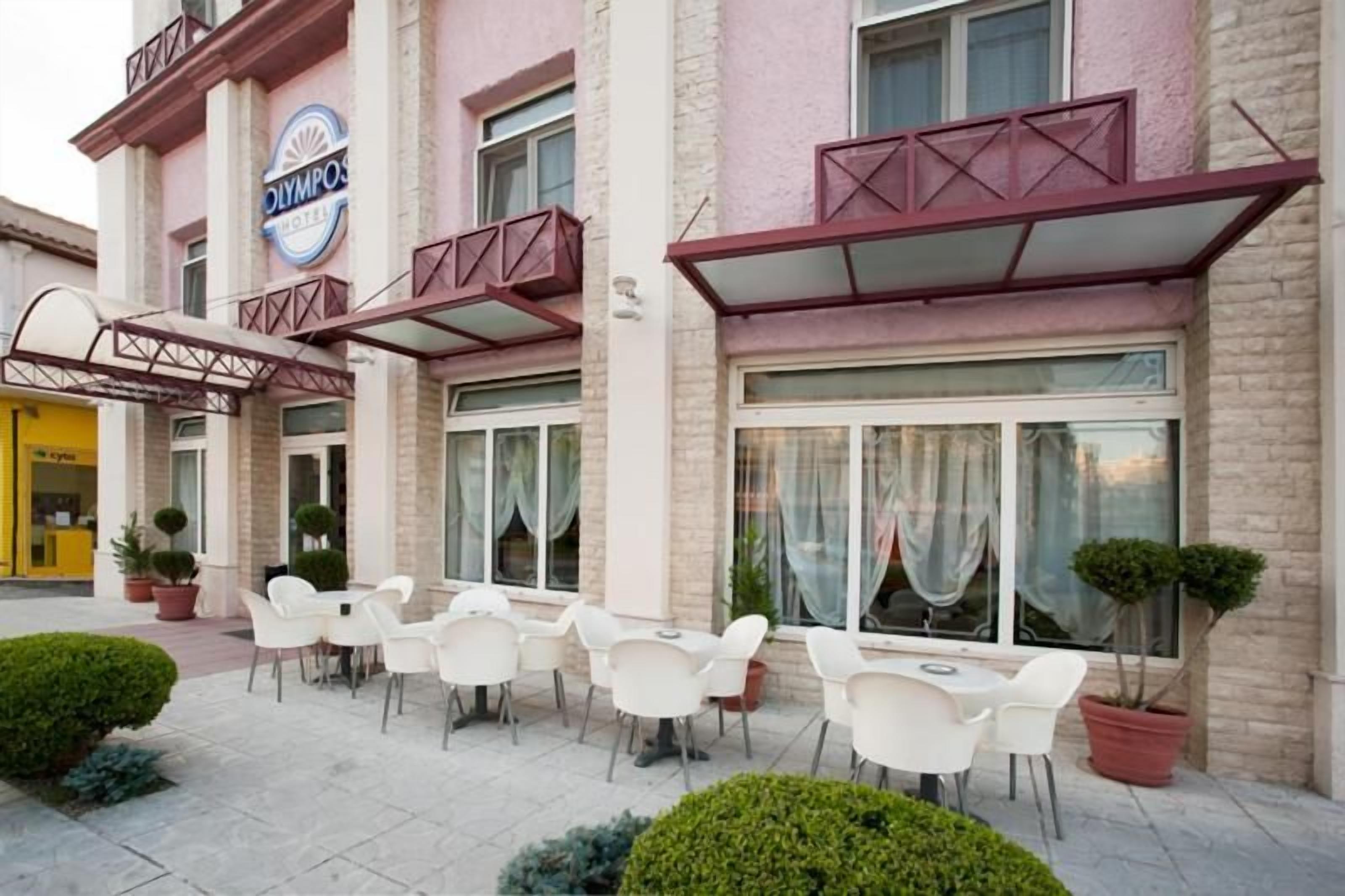 A hotel exterior with outdoor seating and a signboard.