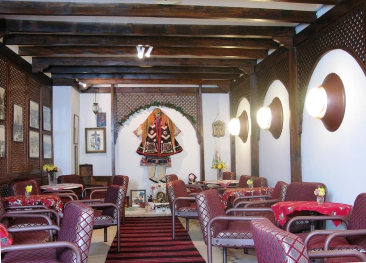 A restaurant with a traditional interior, featuring wooden beams, patterned chairs, and a central decorative archway.