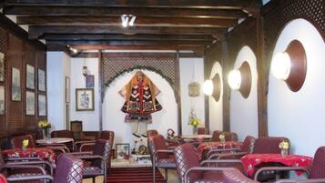 A restaurant with a traditional interior, featuring wooden beams, patterned chairs, and a central decorative archway.